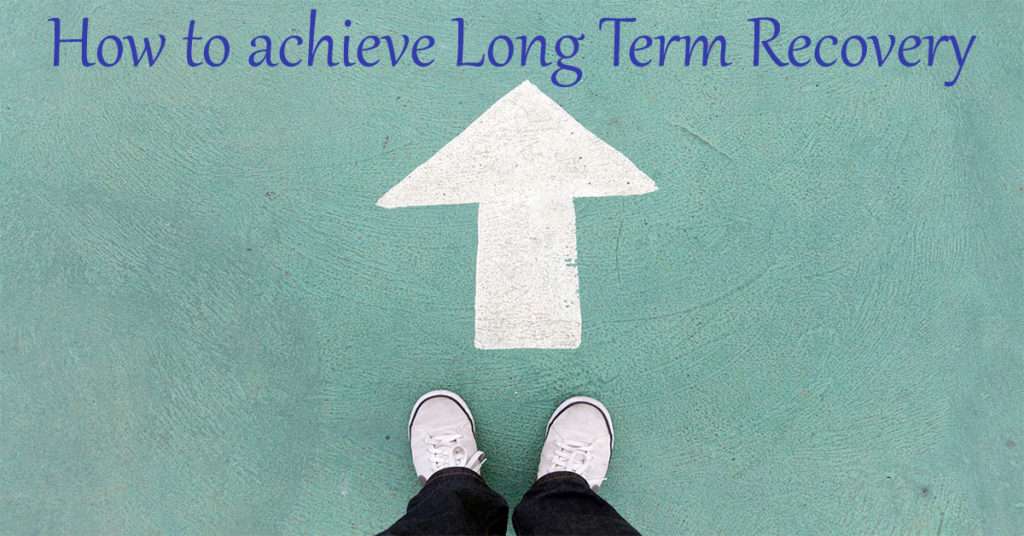 feet standing at an arrow pointing towards a sign that reads how to achieve long term recovery