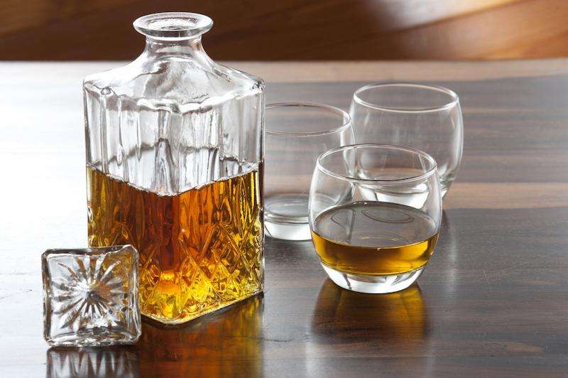 alcohol in an open decanter with three glasses