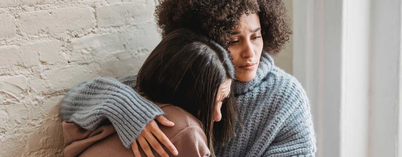 Compassionate woman comforting a distressed friend, offering emotional support during recovery