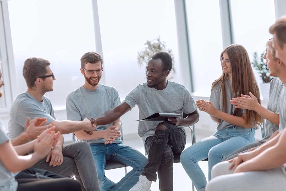 People smiling while in drug addiction recovery group.