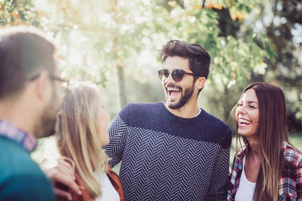 Happy man with sunglasses enjoying time with friends out in nature after taking daily Adderall.