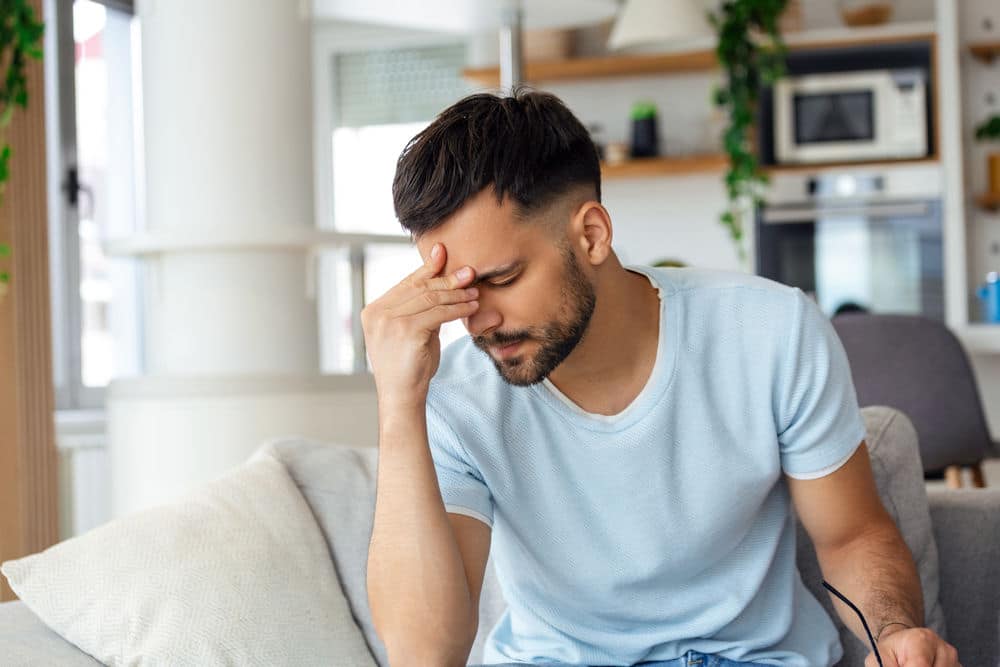 Frustrated young man holding head while learning if Adderall is dangerous.