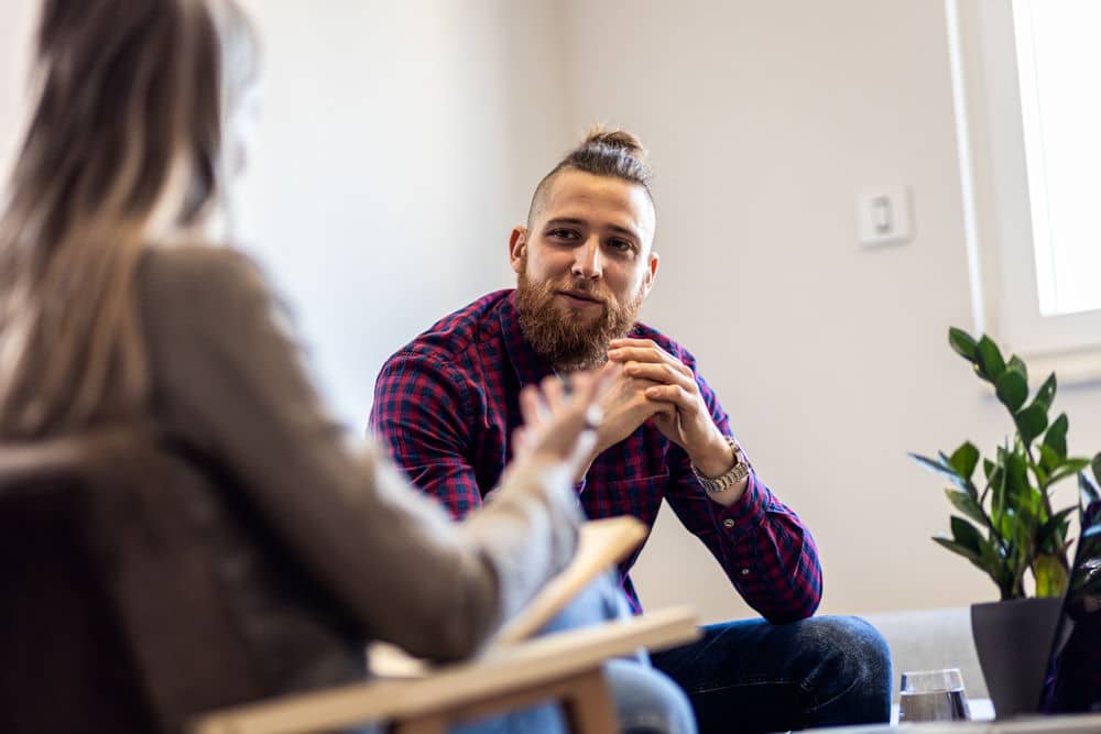 Young man talking to female psychologist during session.