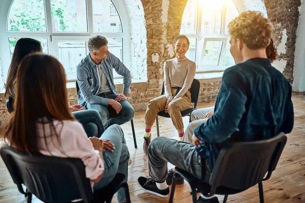 Adults sharing and laughing in a group therapy circle during dual diagnosis treatment in Orange County