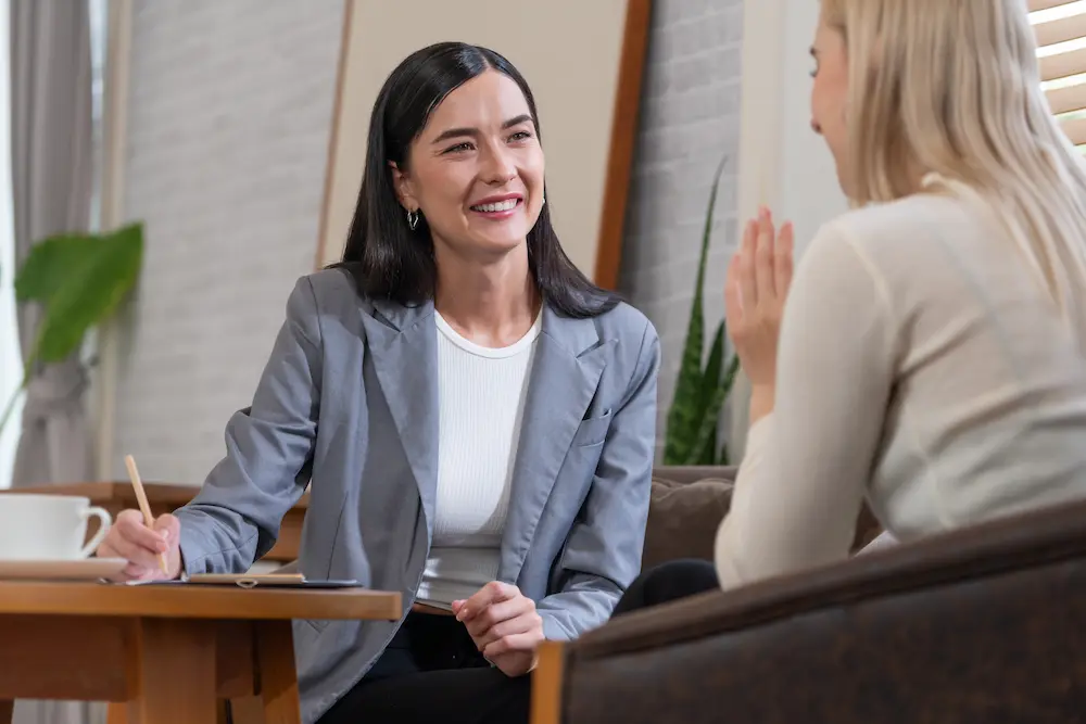 Therapist smiling and taking notes during a one-on-one session, part of dual diagnosis treatment in Orange County